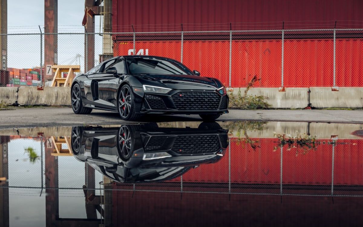 The all new 2020 Audi R8 in metallic black colorway parking at the port with reflection seen on water.