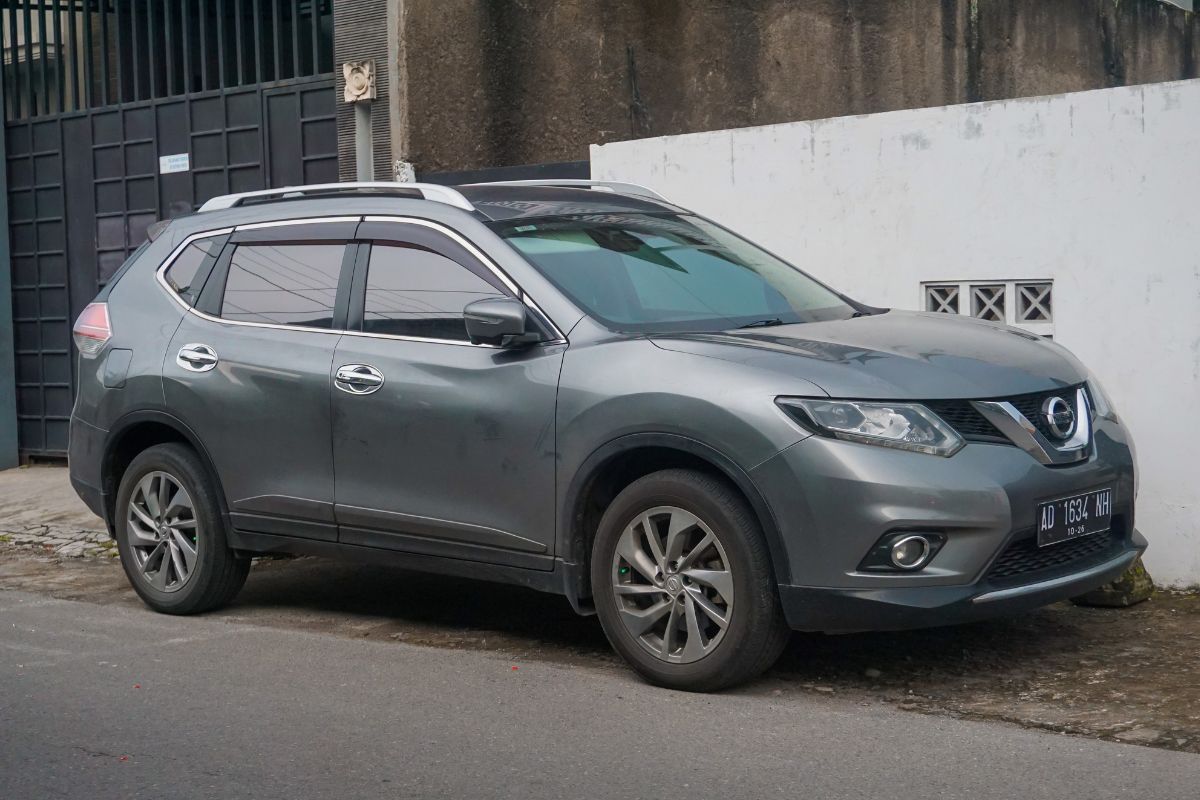 Side view of a grey nissan rogue parked on the side of the road.