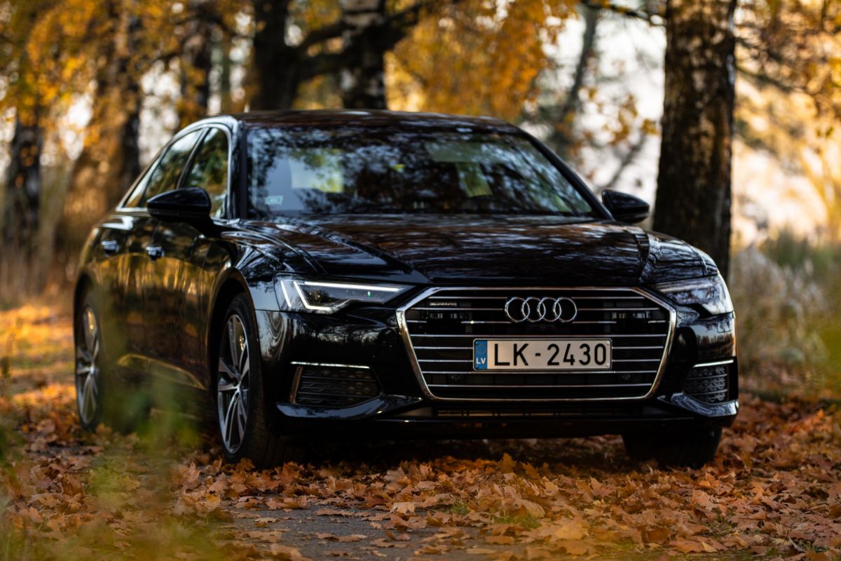 Front view of brand new black audi a6 car with autumn leaves background.