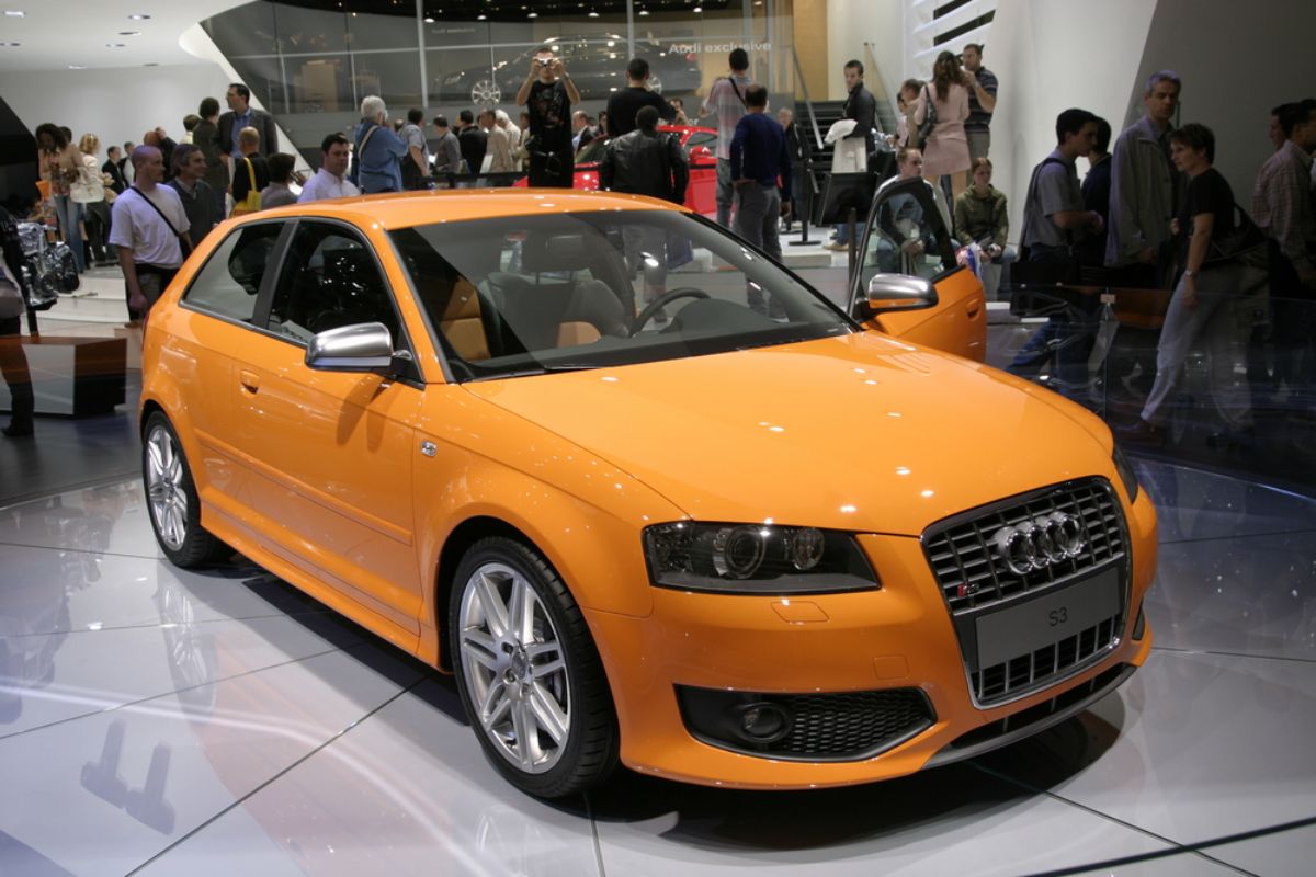 Brand new Audi S3 in a mint orange colorway displayed at an automobile exhibit.