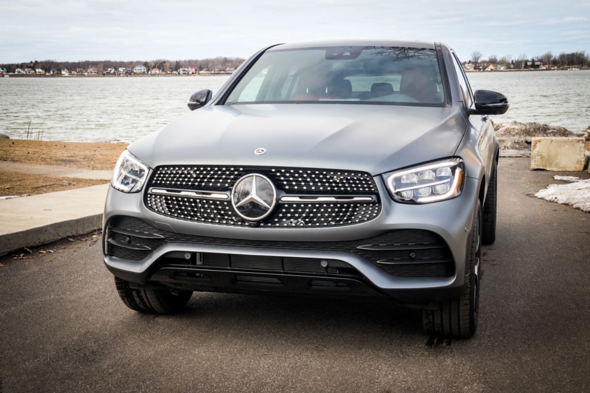 Front view angle of a Mercedenz Benz GLC in a grey colorway captured parking beside a river.