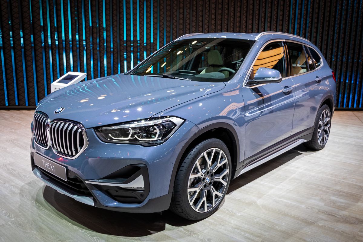 A photo of light blue bmw x1 on auto show spotlighted.