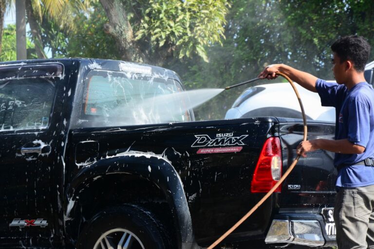 A photo of male worker washing a black dmax double cab pickup.