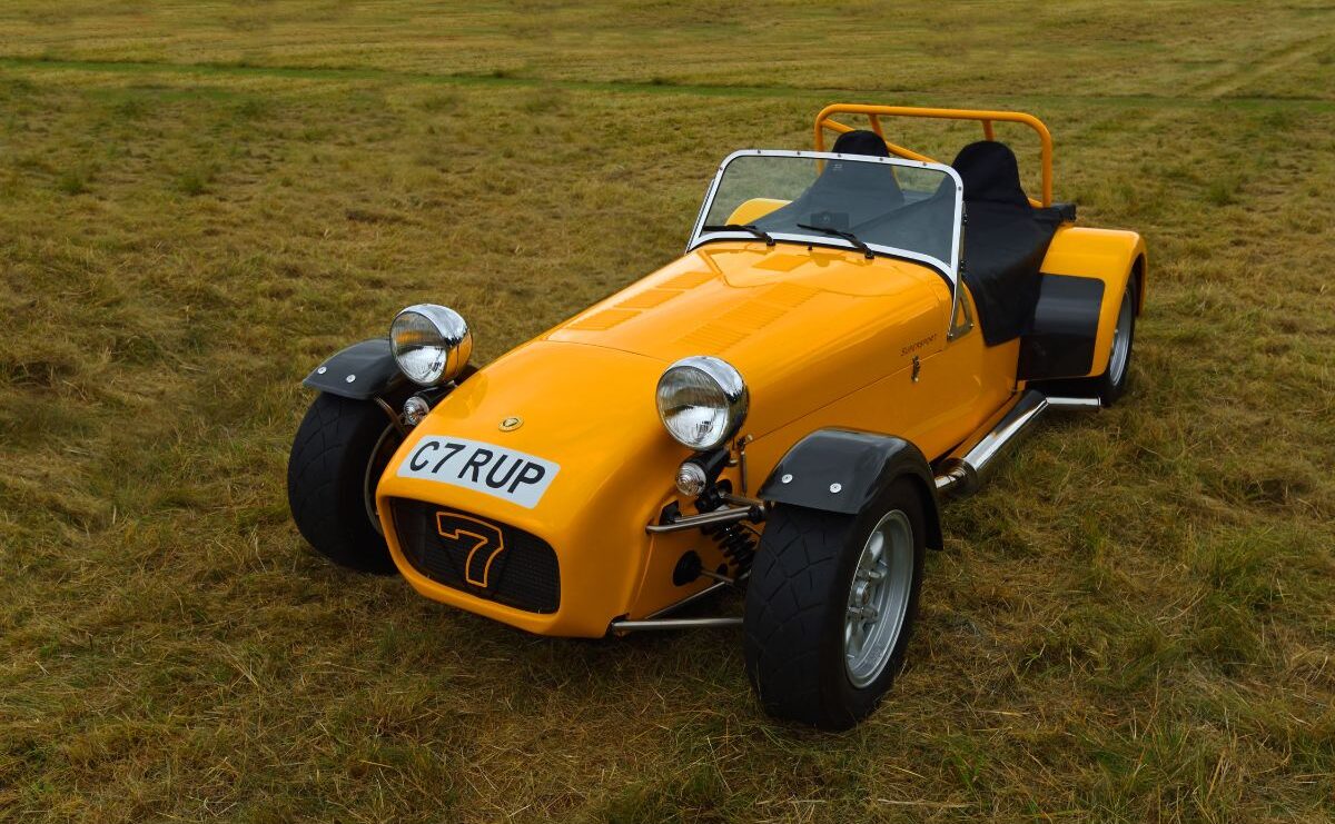 A photo of yellow caterham iconic seven on grass.