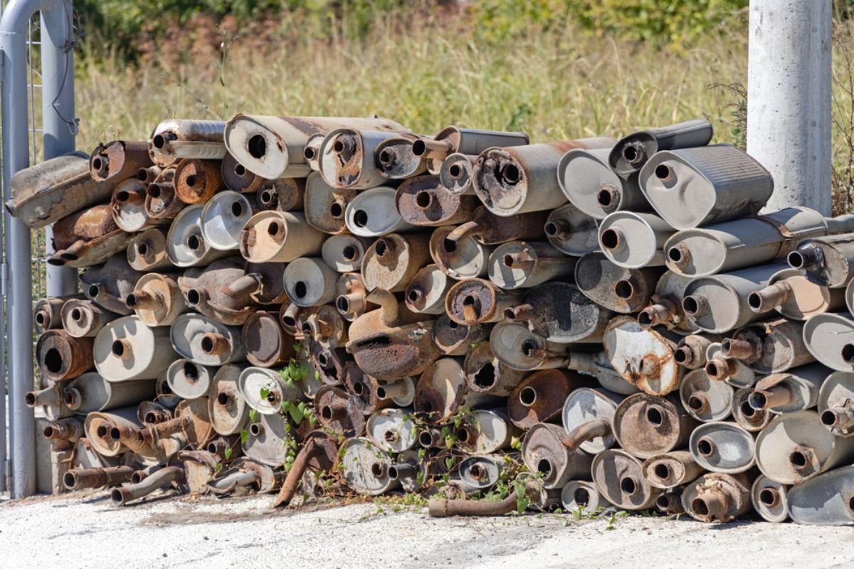 Collection of old rusty and unused car exhaust muffler pipe in a car junk yard. 