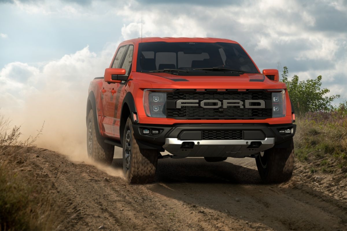 The all new badass Ford F-150 Raptor in a red orange colorway doing test drive in a challenging terrain. 