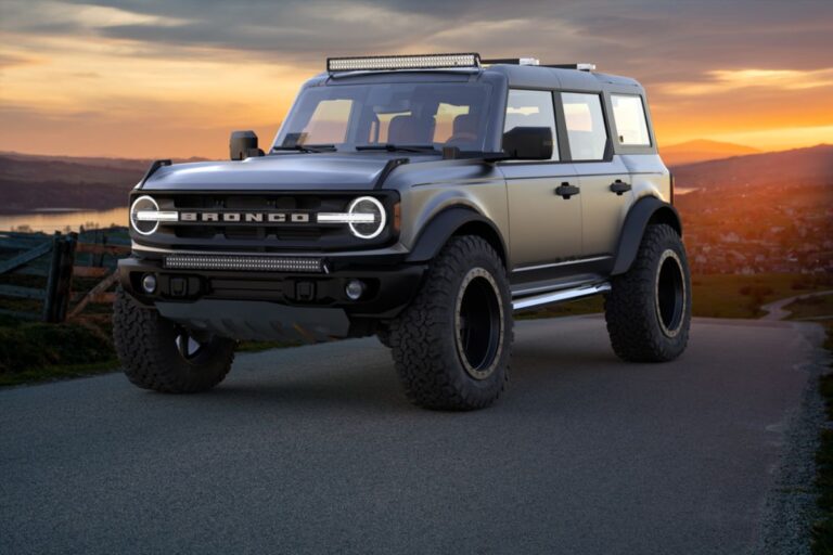 Modern classic Ford Bronco parked at mountainious roads with beautiful sunset in the background.