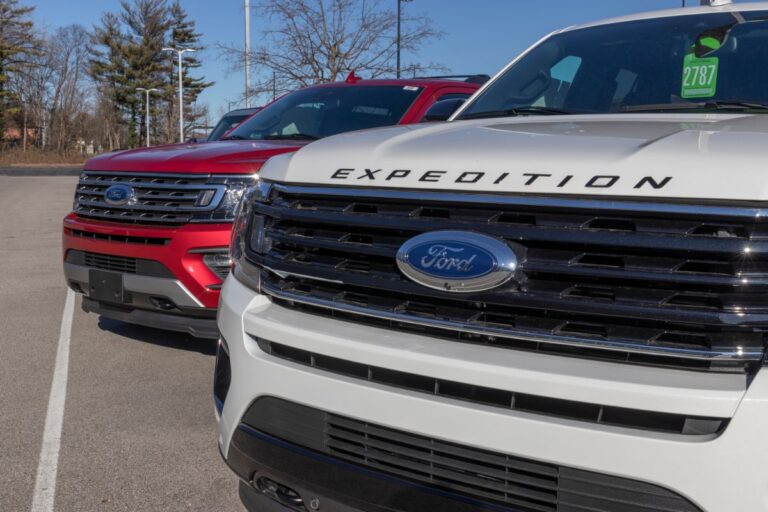 Close up photo of two ford expedition car in a red and white color display at a dealership.