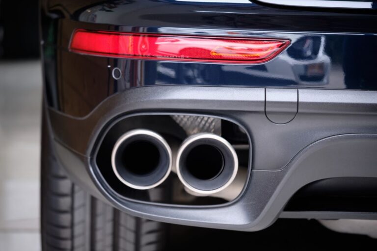 Close up photo of stainless steel exhaust tip muffler pipe of sports car.