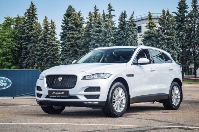 Front and side view of white brand new of jaguar f pace in parking lot.