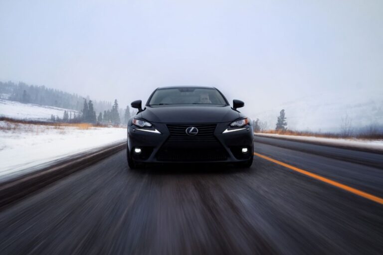 A photo of black lexus is car driving in road during winter.