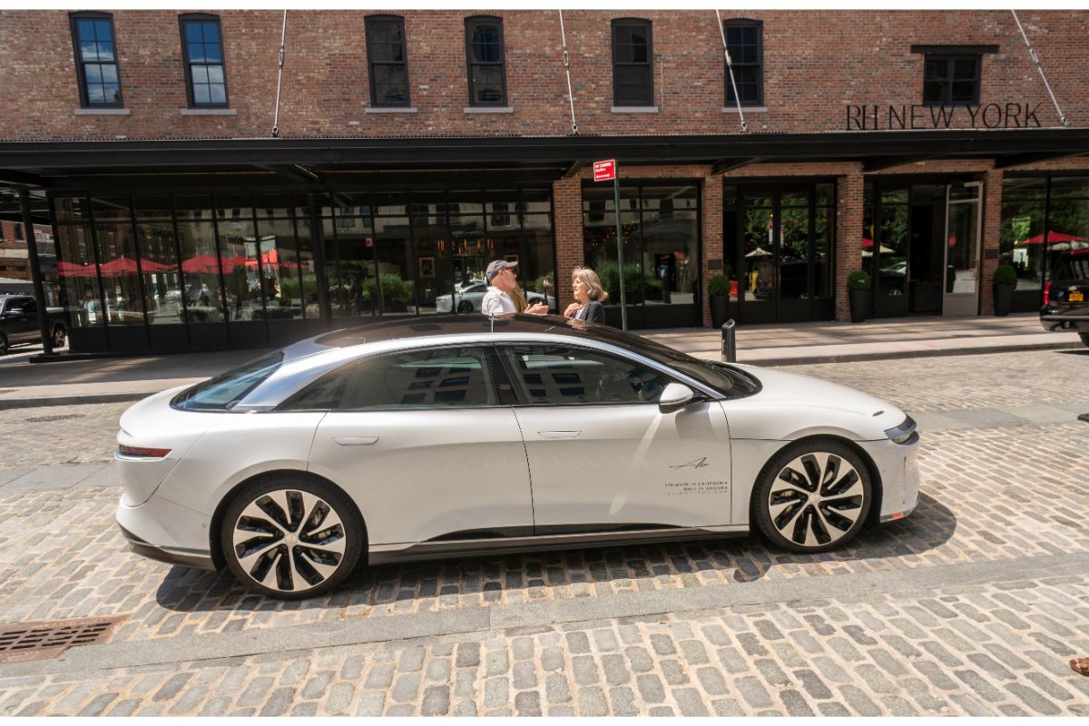 Side view of white lucid air car displayed outside in city street.