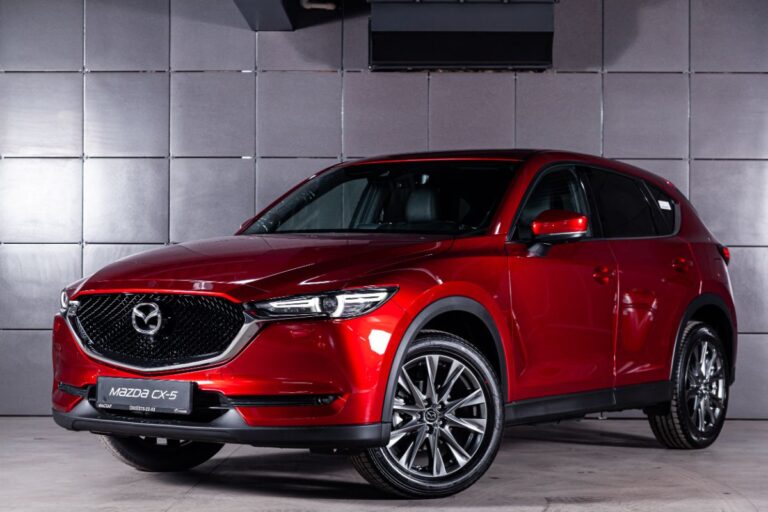 Side view angle of a brand new red Mazda CX-5 at a dealership store.