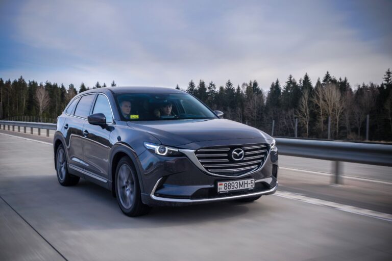 A photo of black maxda cx 9 car driving in the city street.