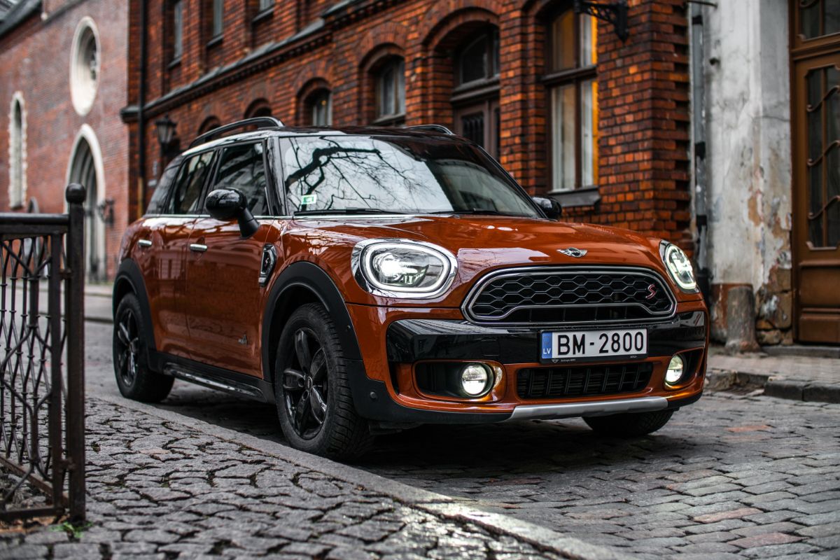 A photo of brown mini countryman car in parking lot with a classic backround.