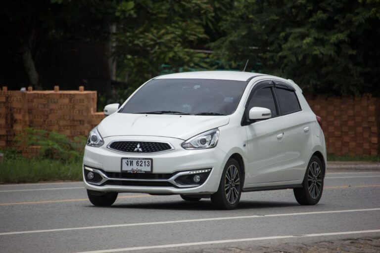 A photo of white mitsubishi mirage driving on the street.