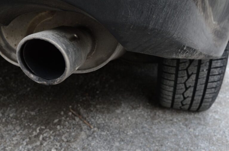 A closeup photo of a dirty car muffler exhaust setup.