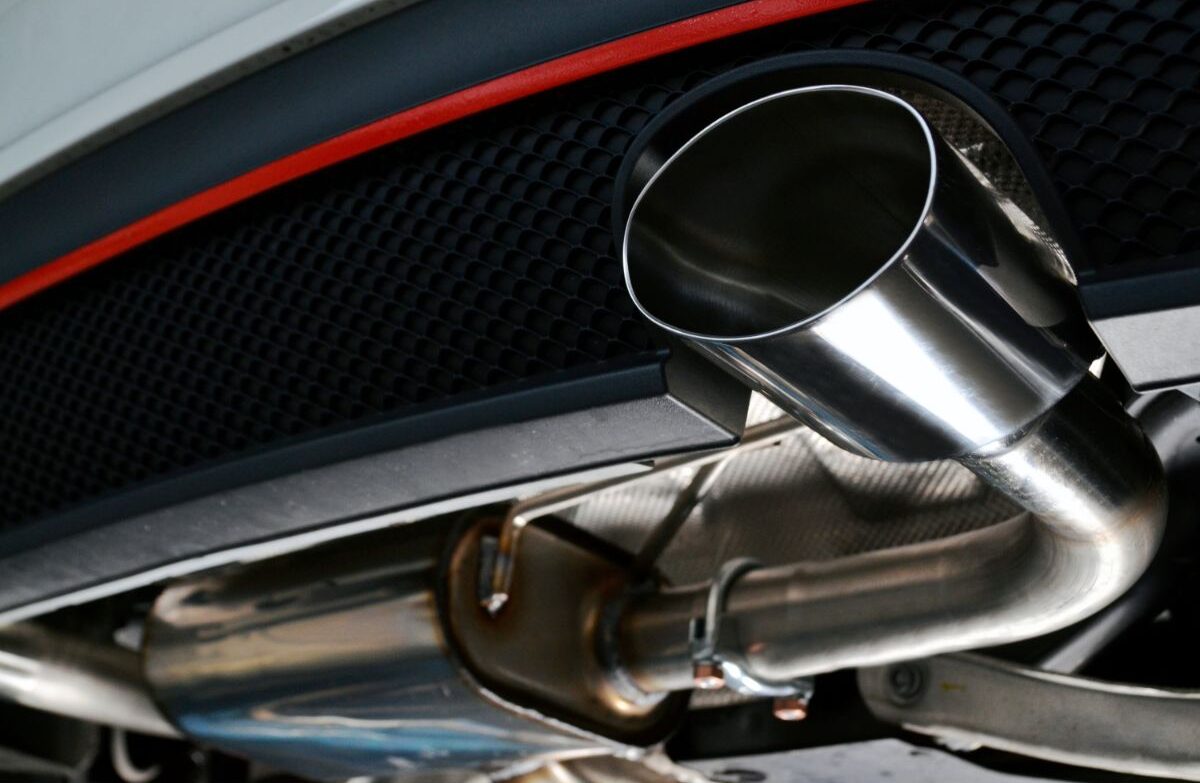 Close up photo of exhaust Tailpipe chromed made of stainless steel on powerful sport car bumper.