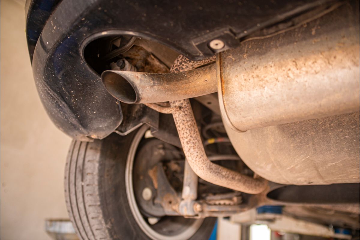 Zoom in image of an old and rusty car exhaust pipe with poor conditions and performance.