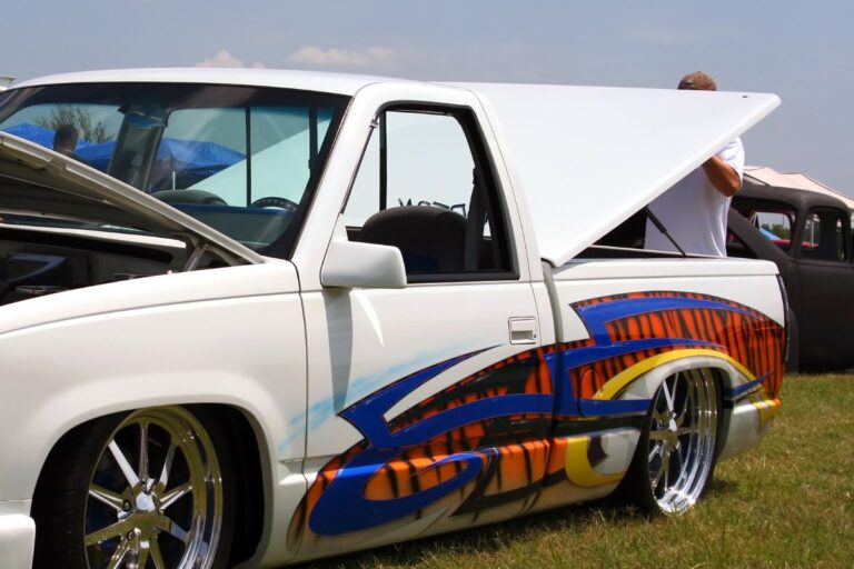 Cropped photo of a white truck with paint at the side.