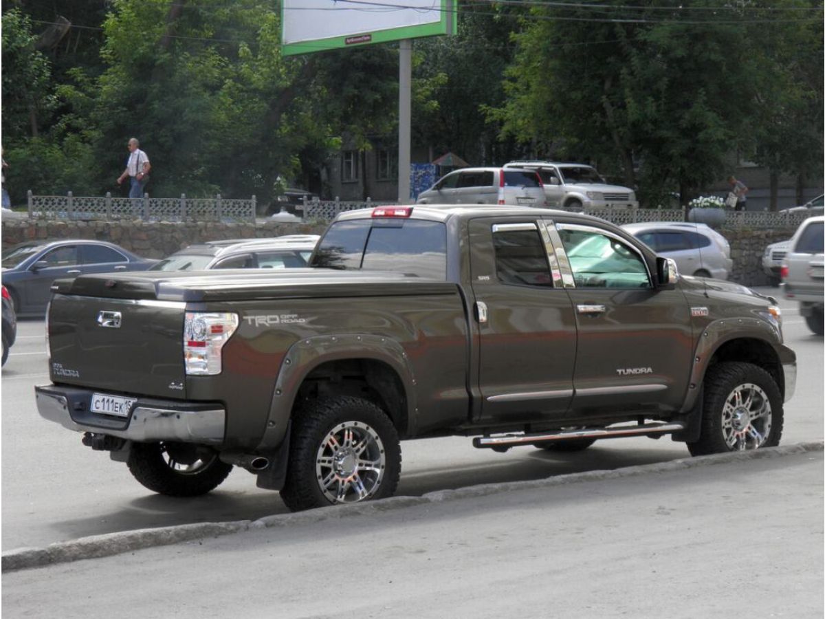 A metallic brown pick up truck wit tonneau cover parking beside the street.