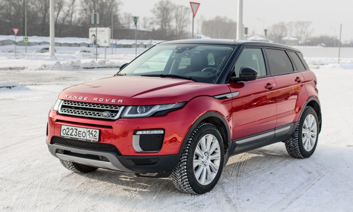 Front and side view of red range rover evoque photographed on snow road winter climate.