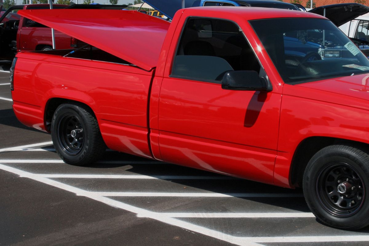 A cropped photo of red chevy truck using tonneau cover.