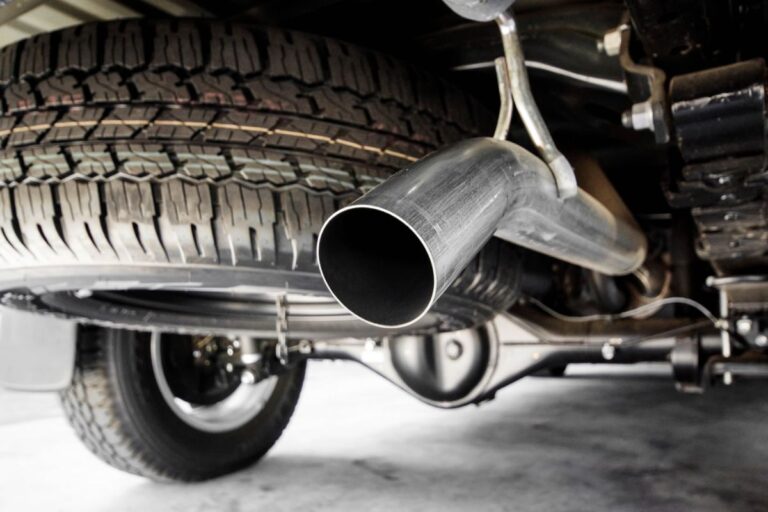 A zoom in photo of a single muffler in a pick up truck.