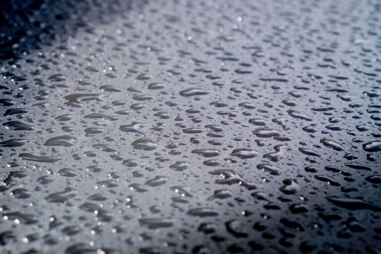 Close up photo rain droplets on black surface.