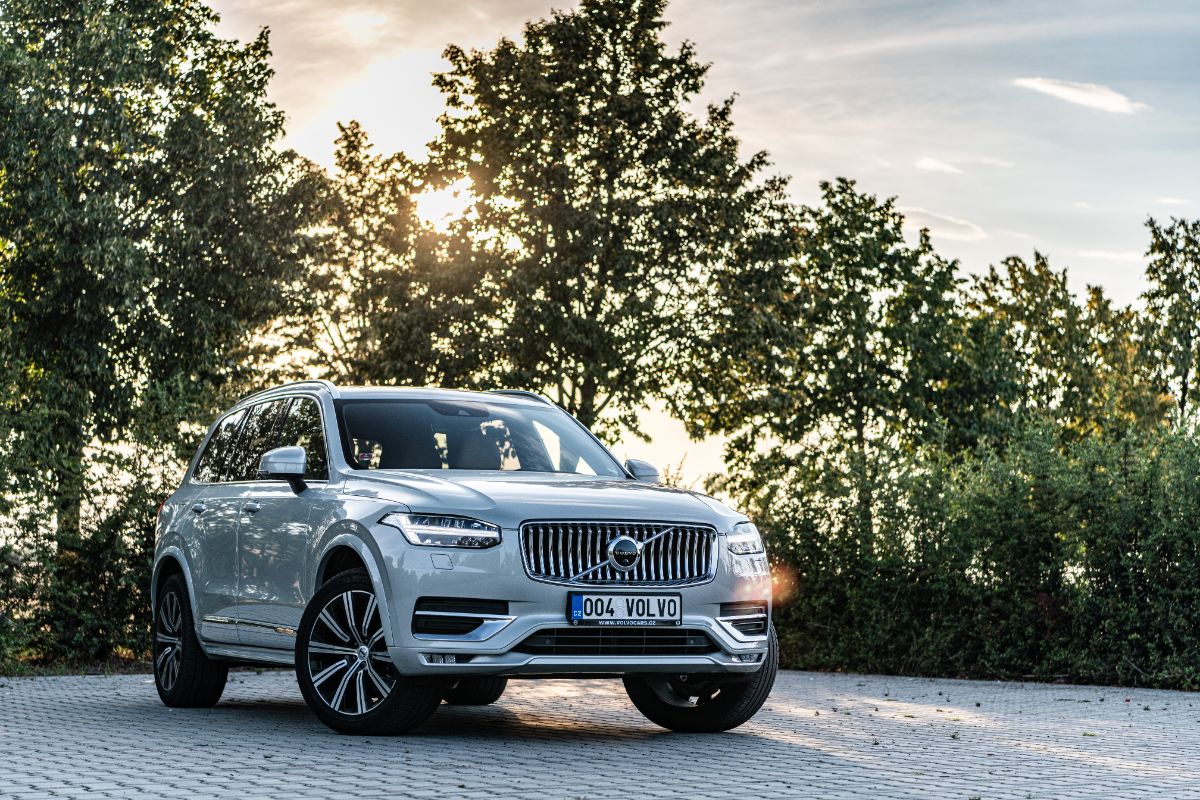 A photo of volvo xc60 car displayed outside with trees background.