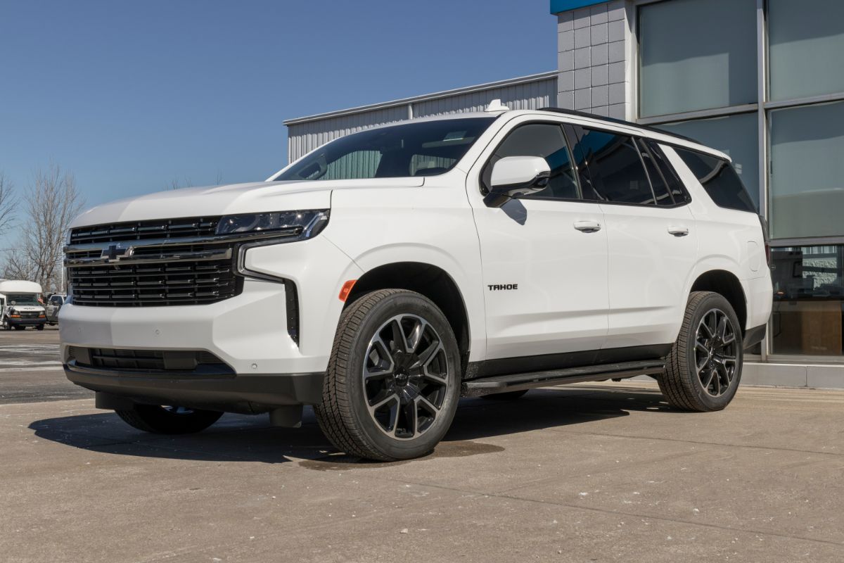 A white Chevy Tahoe displayed at a dealership is seen from a low perspective.