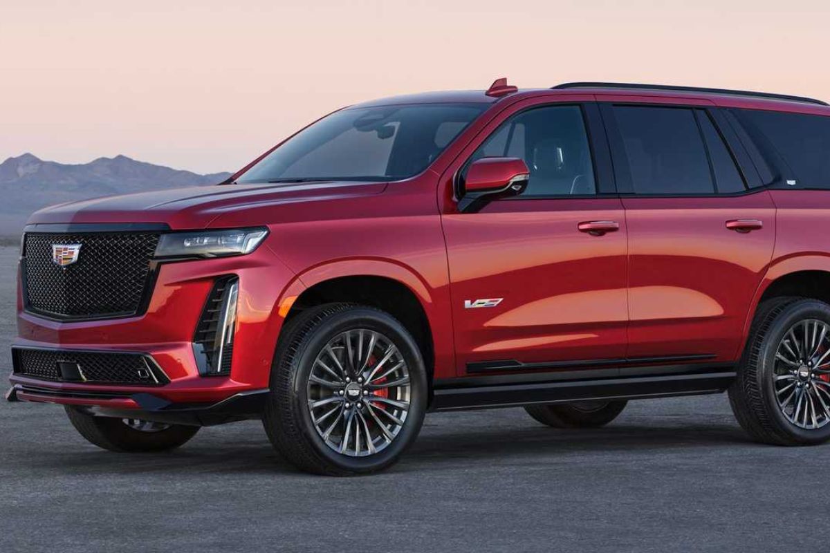 View from the side of a red 2023 Cadillac Escalade with mountains in the background.