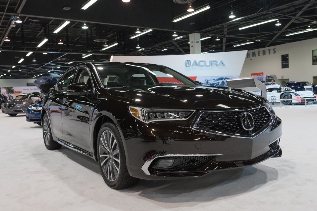 Display of glossy black Acura TLX together with other cars at the back.