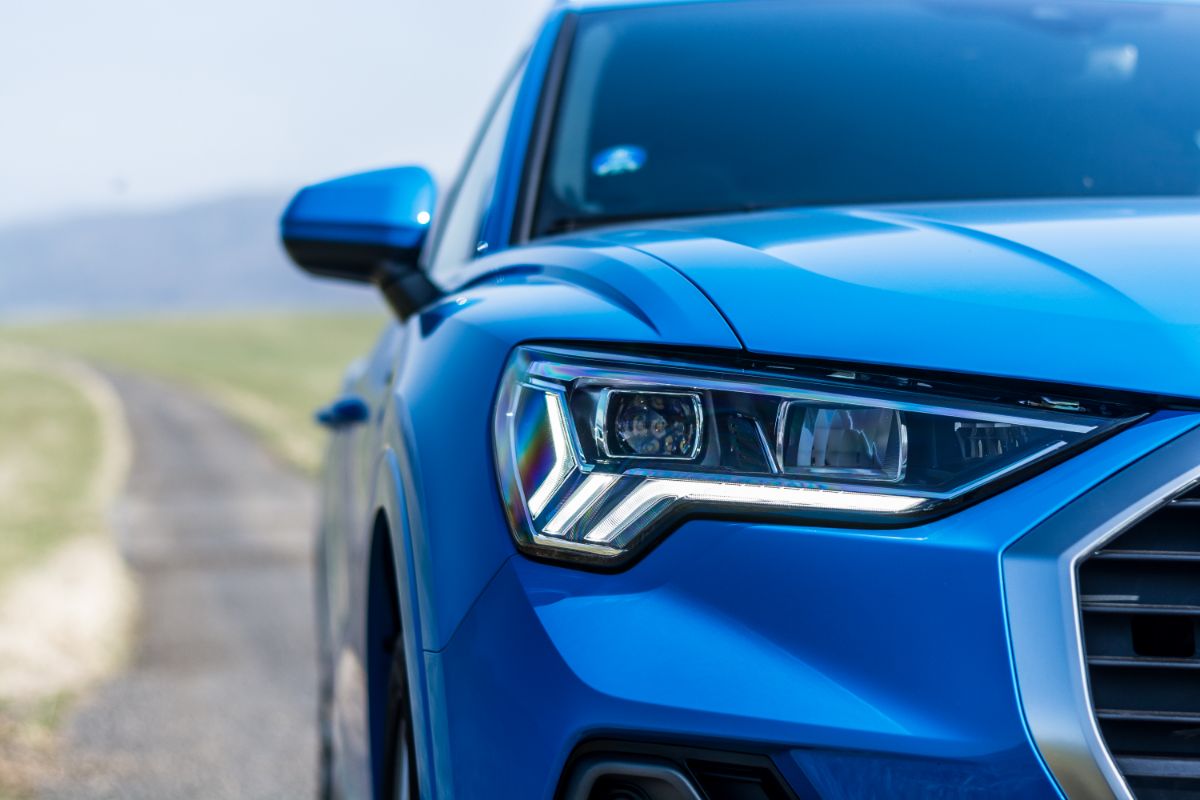 Close-up photo of the front light of a blue Audi 4 on a blurry background.