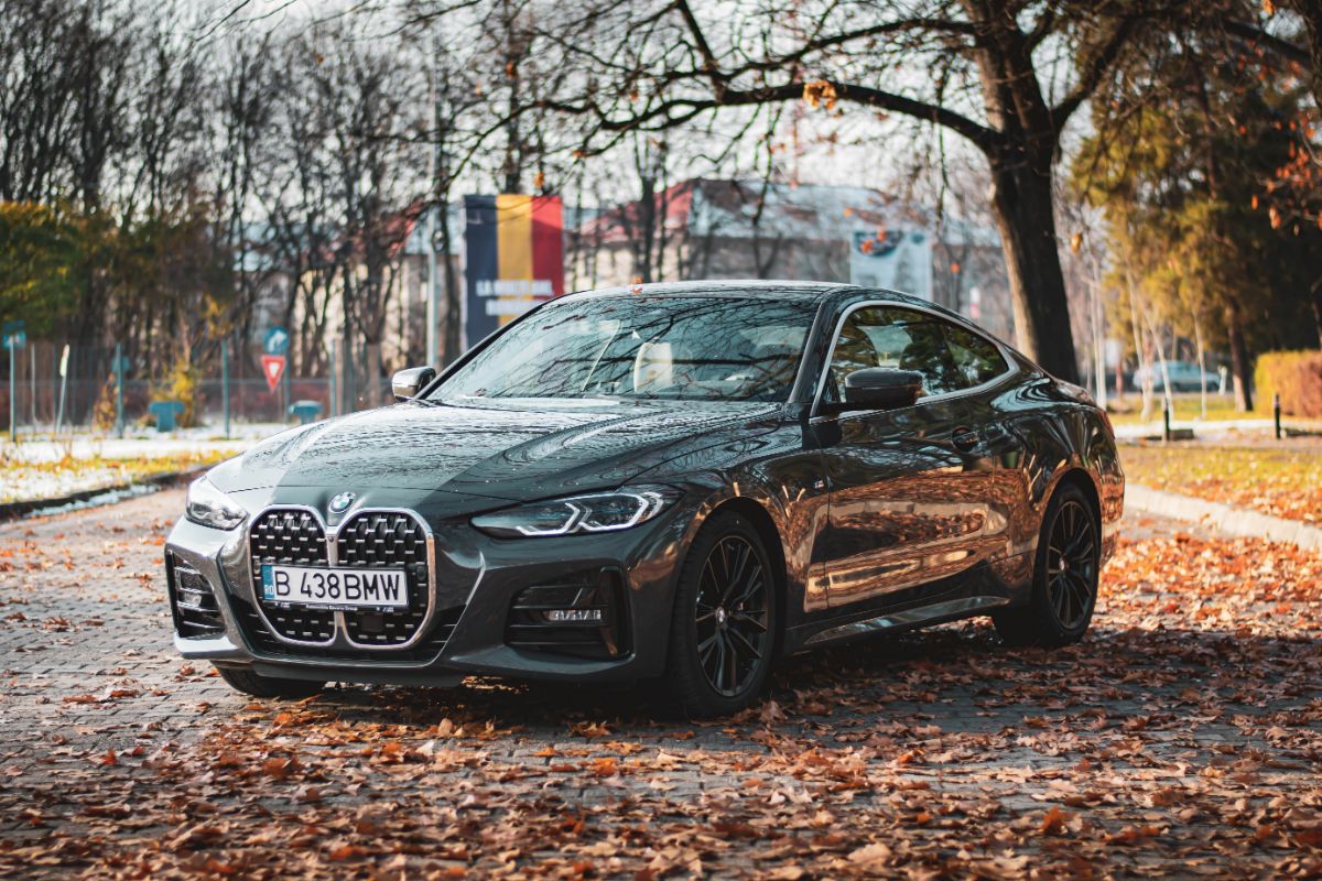 A glossy black BMW 4 Series parked during fall season.