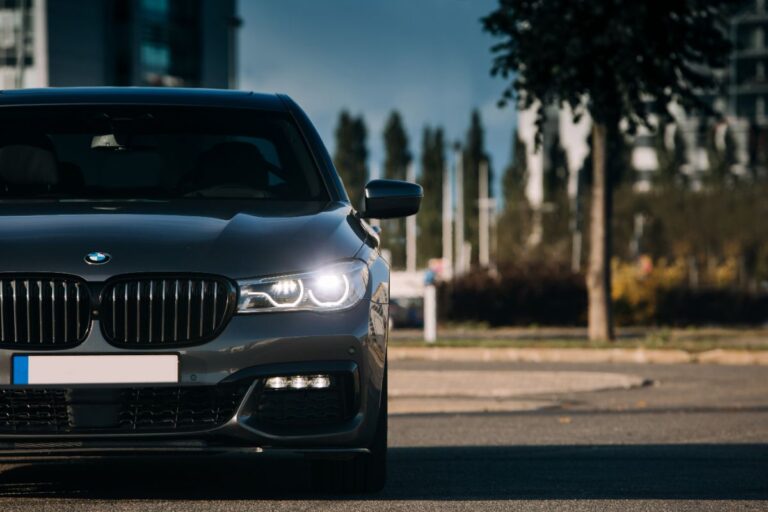 Close up shot of a black BMW 7 Series with front lights on.