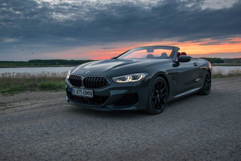 Grey BMW 8 Series with an open roof parked by the river.