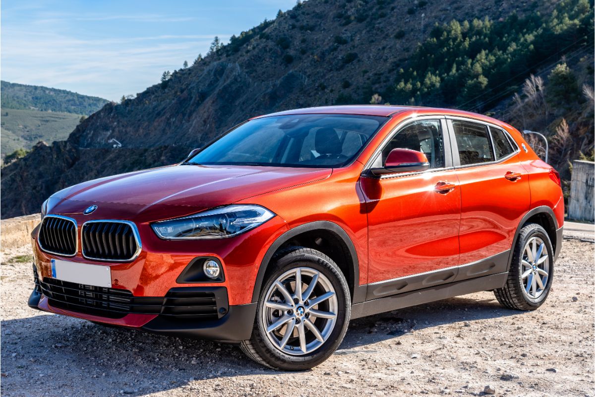 BMW X2 car parked at dirt road in mountains.