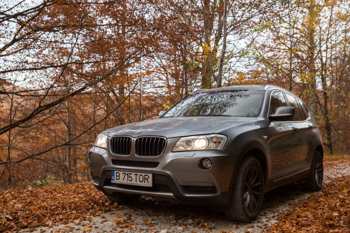 A view of bmw x3 driving on a typical autumn landscape.