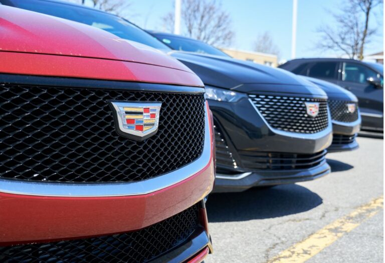 Close up photo of a Cadillac Ct5 card in different colorway being displayed outside an auto dealership store.