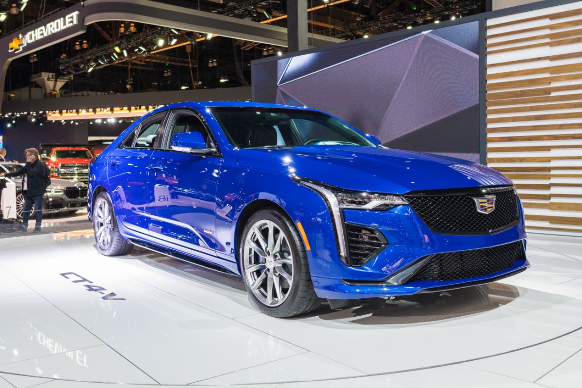 Display of gleaming blue Cadillac CT4 in an auto show.