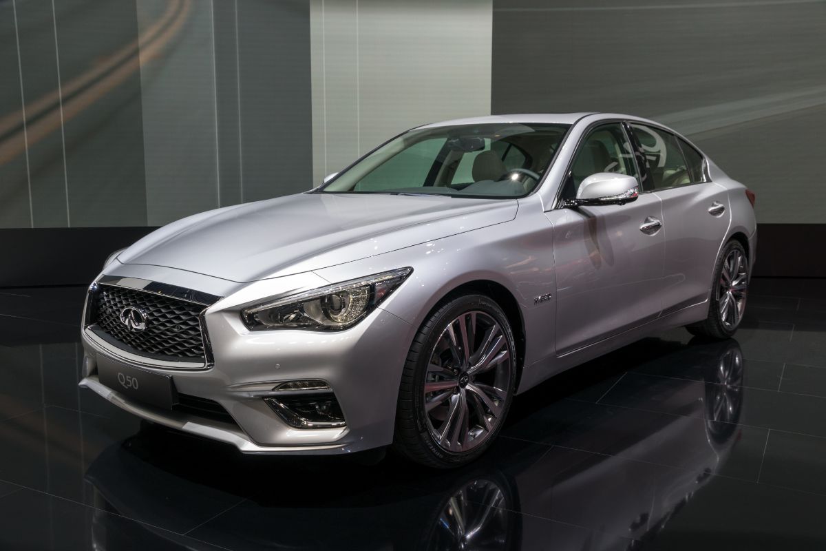 Silver-colored Infiniti 60 car presented on a glossy floor with a gray wall background.