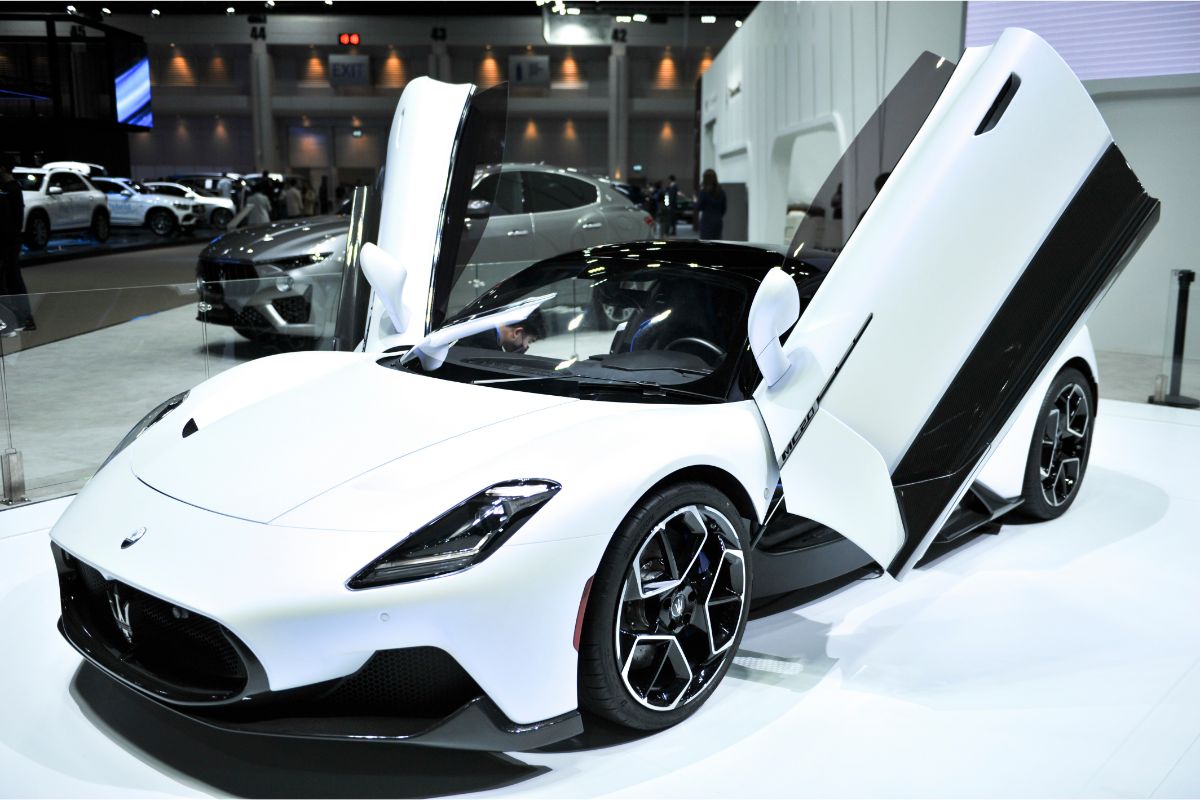 Two doors of a flashy white Maserati MC20 automobile at the auto show opened.