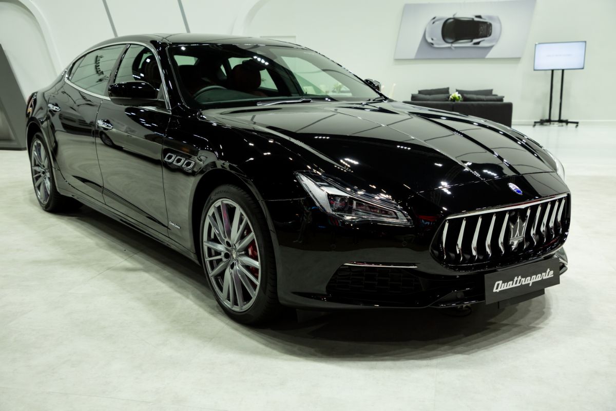 Front side view of a glossy black Maserati Quattroporte on display.