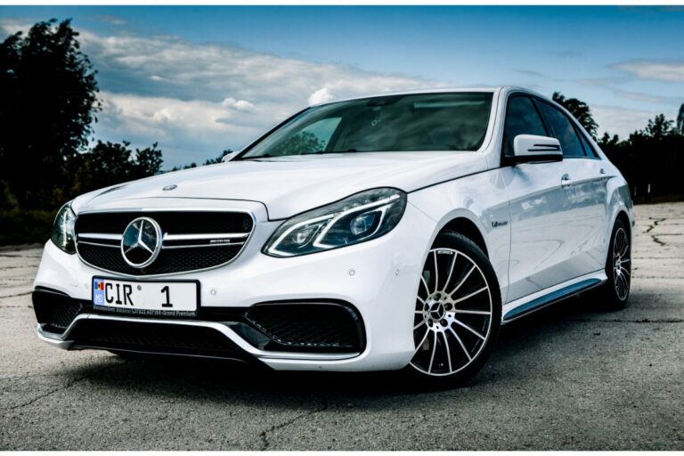 Front view of a white Mercedes-Benz E-Class Sedan parked on a crack road.