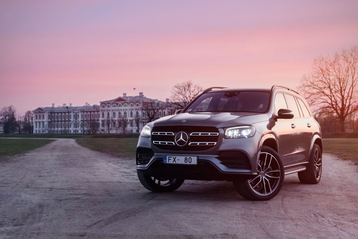 Front view of Mercedes-Benz GLS-Class parks by castle palace at sunset background mood.