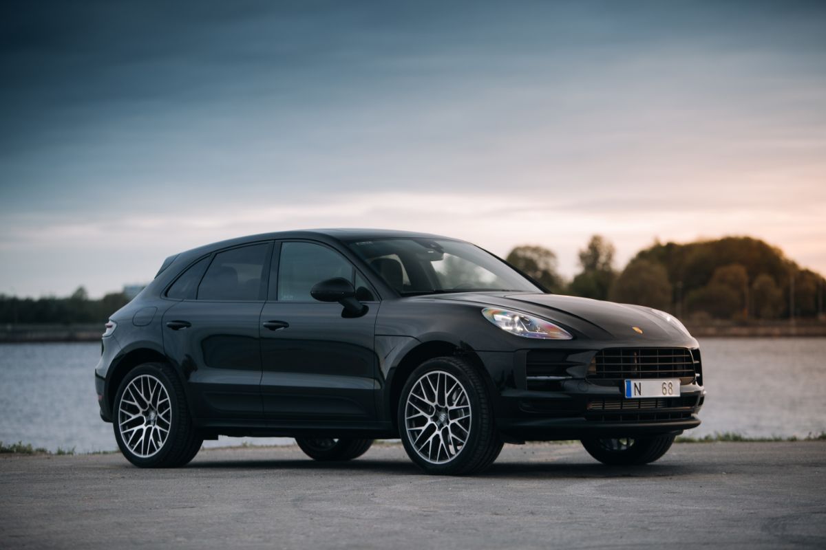 A black Porsche Macan car parked near the mesmerizing river.