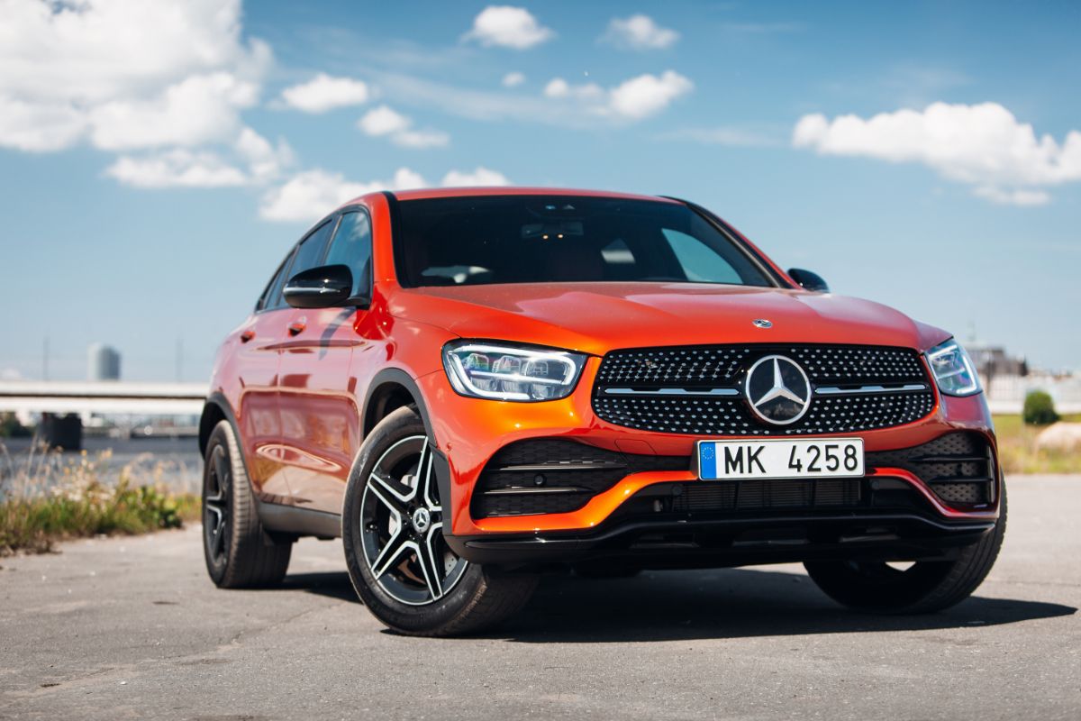 Orange New Mercedes GLA parking near the river overlooking the bridge.