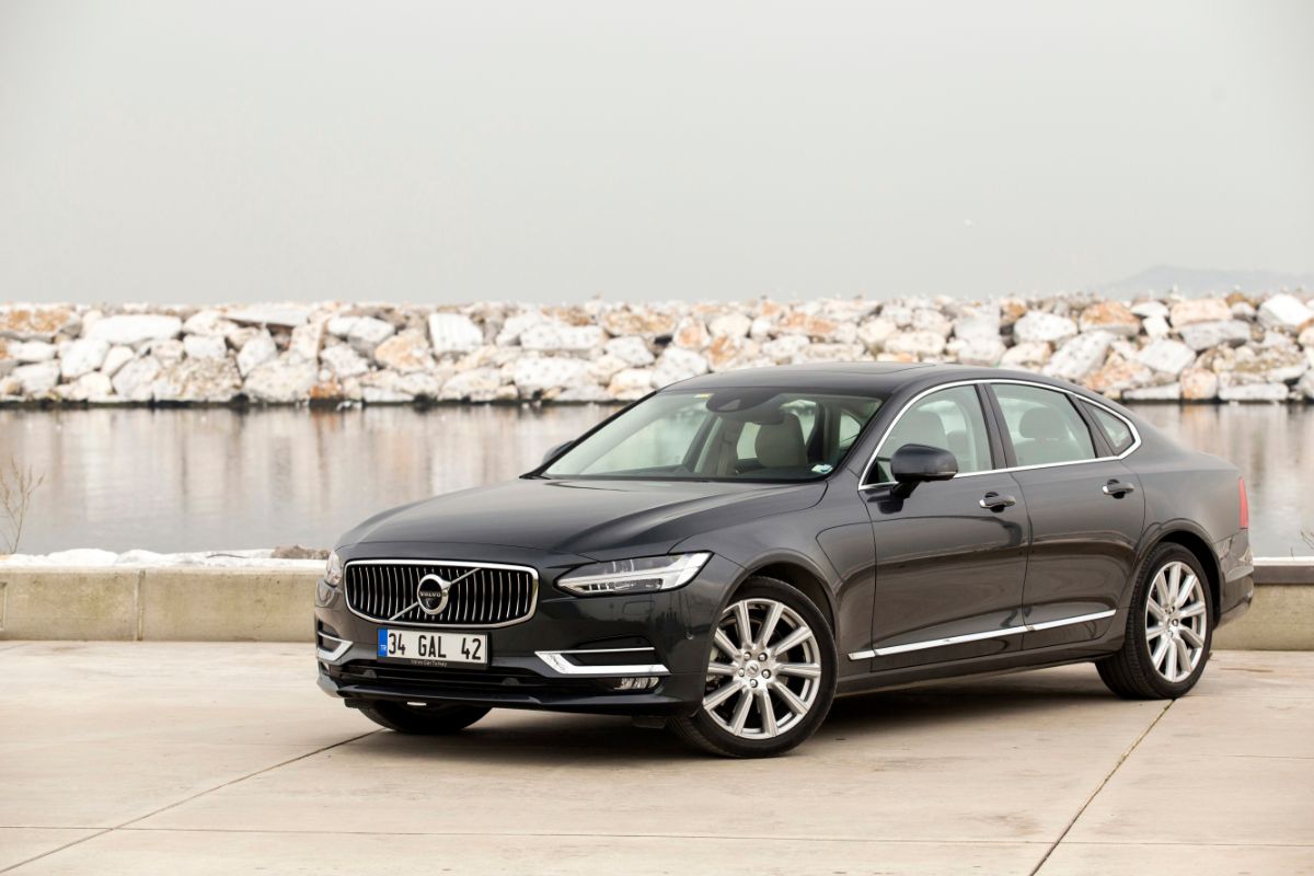 Side view shot of black Volvo S90 car parked near river.