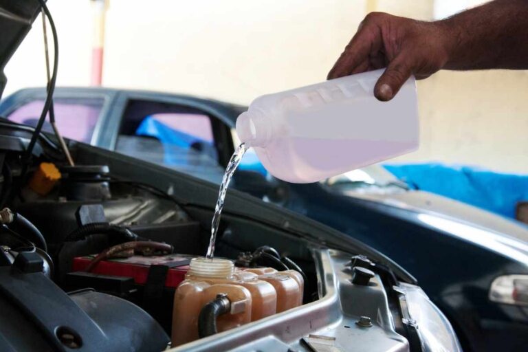 A man pouring coolant in his car's radiator,